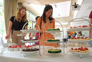 Guest choosing their afternoon tea with a selection of cakes and scones in the foreground.