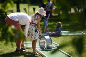 Girl and her father playing mini golf