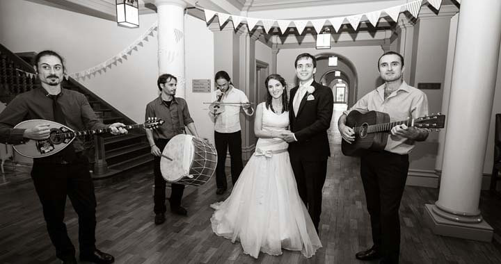 black and white image of bride and groom with musicians holding their instruments